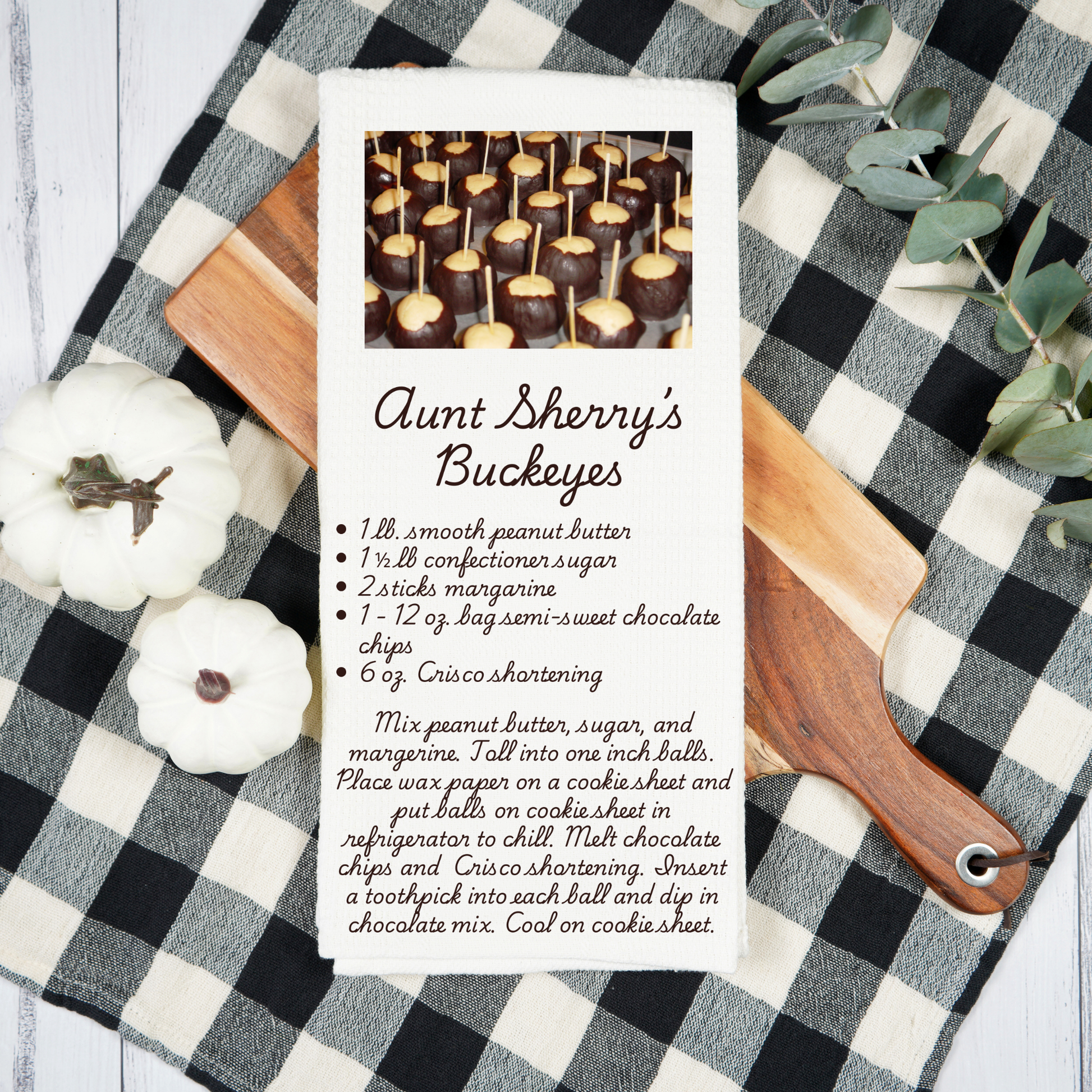 Recipe card for Aunt Sherry's Buckeyes on a checkered tablecloth with pumpkins and a cutting board.