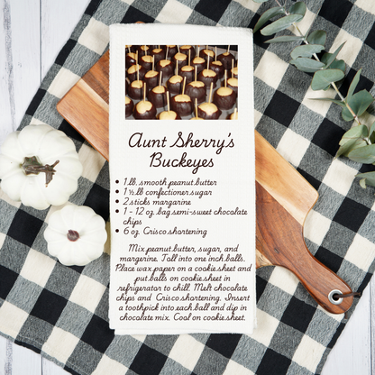 Recipe card for Aunt Sherry's Buckeyes on a checkered tablecloth with pumpkins and a cutting board.