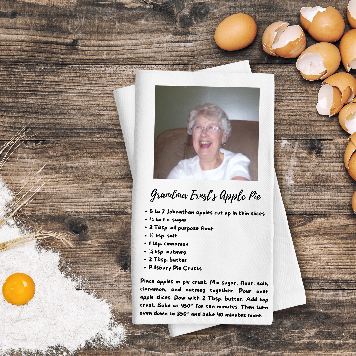 Recipe card for Grandma Ernst's Apple Pie with a photo of an elderly woman on a wooden surface with eggs and flour.