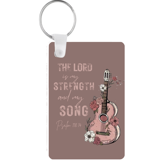 Keychain with guitar design and 'The Lord is my strength and my song' text on a brown background